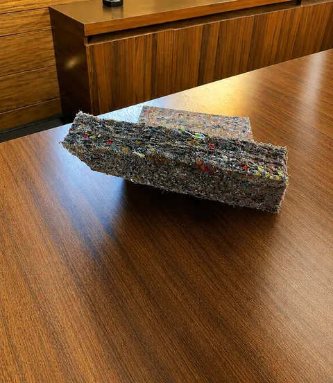 Raw recycled felt sheet on a table, showing the material's fibrous texture